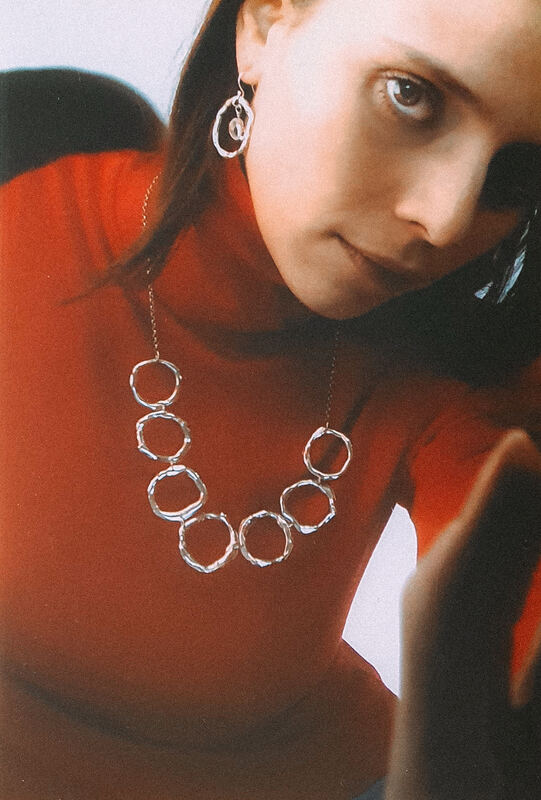 Fanny in a red top wearing a necklace of linked open silver cells