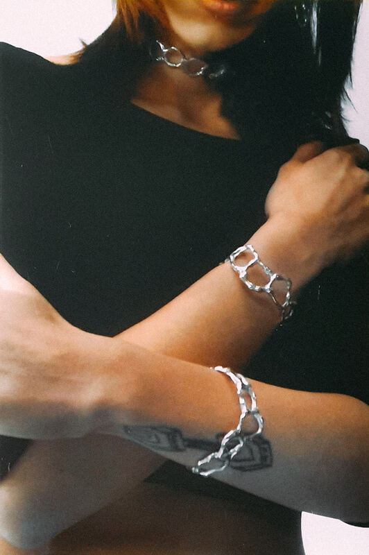 Arms crossed in black, an openwork cuff on each wrist