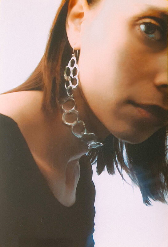 Close portrait with a long earring of linked silver cells