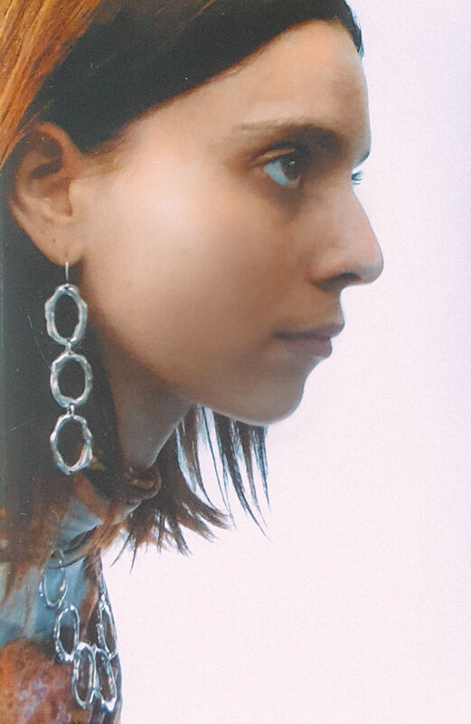Profile with a long drop earring of linked cells