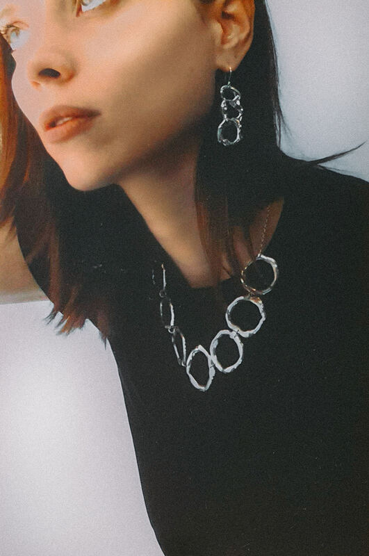 Looking aside in black, with a cell necklace and a drop earring