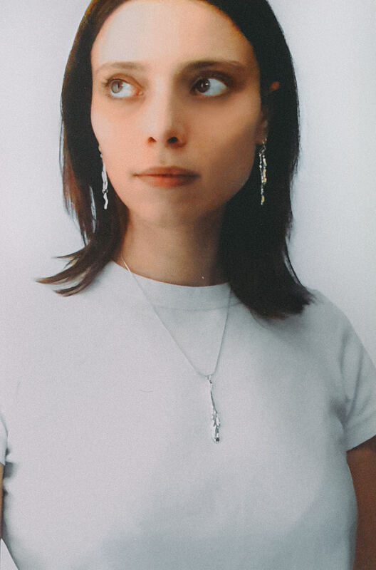 In a white T-shirt with a fine pendant and long earrings