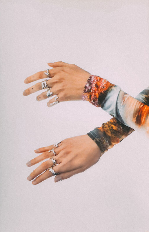 Two hands reaching into the frame, rings on every finger