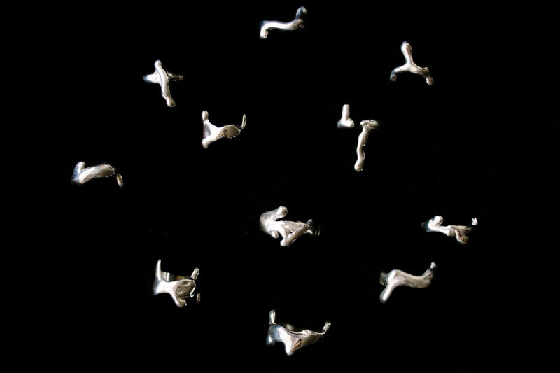 Small sculptural silver pieces scattered on black