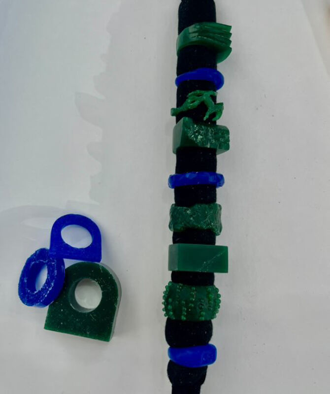 Rings carved in green and blue wax, stacked on a ring mandrel